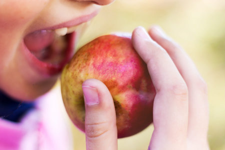 Young girl biting ripe juicy appleの写真素材
