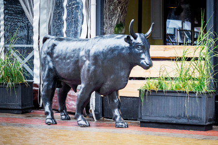 Sculpture of a bull in the street of a modern cityの写真素材