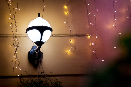 Lamp and garlands on the wall of the house during Christmas and New Year holidays. Copy spase for textの写真素材