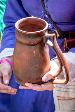 A woman in medieval clothes holds a clay pot in her handsの写真素材