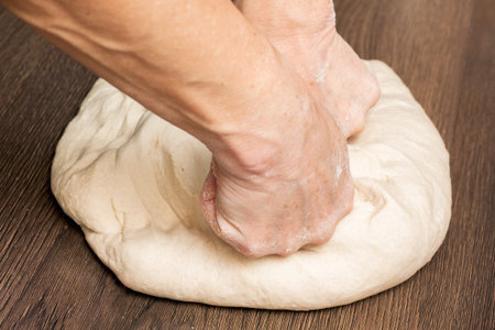 The woman kneads down the dough for the preparation of bread or ravioli