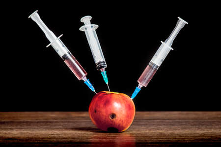 Three syringes are inserted into the apple with rot traces. Adoption of drugs. The problem of drug addiction. Intensive therapyの写真素材