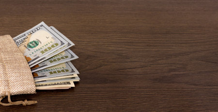 A bag of money on a dark wooden background. Copy space