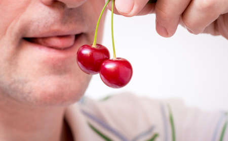 A man holds cherries in his hand and wants to eat it. Seductive cherriesの写真素材