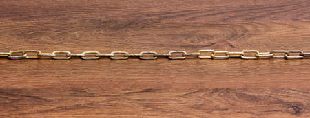 The straight chain is lying on a wooden tableの写真素材