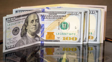 Dollars lie on the clock and mirrored in the glass of the watch. Time to earn money. Time is moneyのeditorial素材