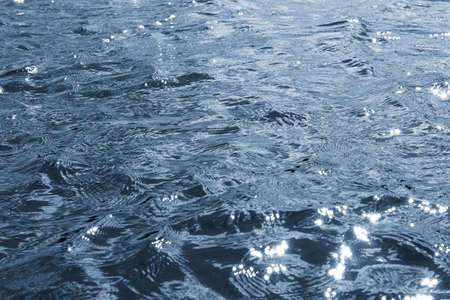 Background, texture from dark waves, in which the sun reflects. Dark waves on the surface of the river in windy weatherのeditorial素材
