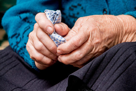 An old grandmother holds a handkerchief in her hands. The hands of an old woman