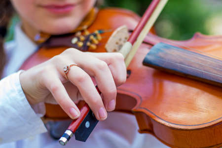 The girl plays the violin, the girl's hand with fiddle bowの写真素材