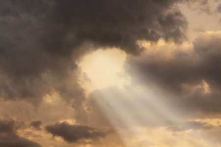 Sunlight penetrates through thick dark clouds during the sunset