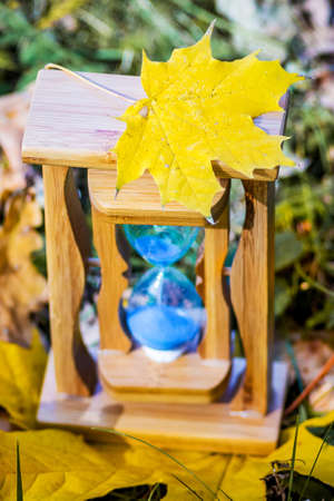 Yellow maple leaf on a sand clock in the autumn forest. Autumn timeの写真素材