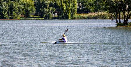 Woman floats on kayaking on the river along the shore with trees