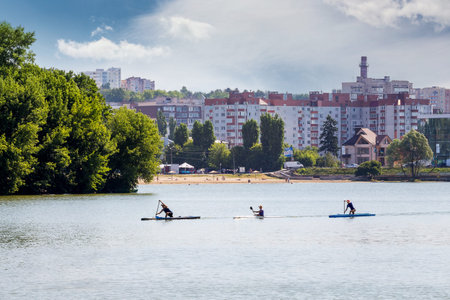 Active rest on the lake near the modern city. Athletes swim in kayaks