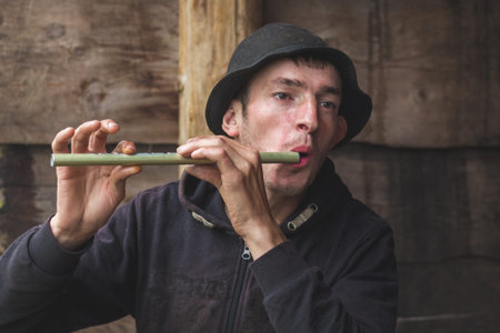 Ukraine, Yaremche. July 2019. Young guy from the mountainous terrain plays on a reed pipe, panpipe....