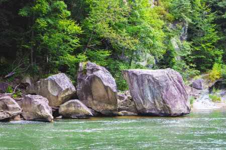 Mountain river with huge stones on the shore in summer. Picturesque waterfall in Yaremche, Ukraine