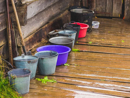 Agricultural equipment under the house in rainy weather. Bucket and bowl on a wood floorの写真素材