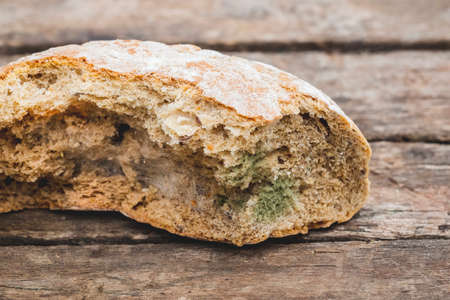 Mildew on a slice of bread, lying on a wooden surface. Stale bread, covered with mildewの写真素材