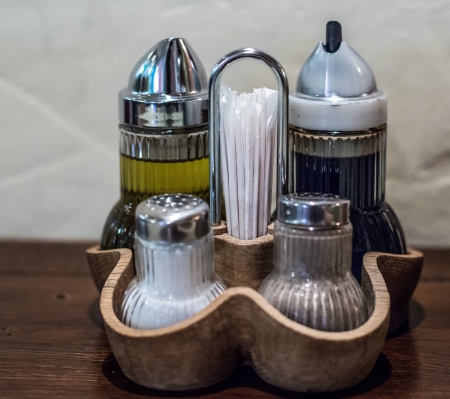 Oil and vinegar bottles, salt and black ground pepper set on a tableの写真素材
