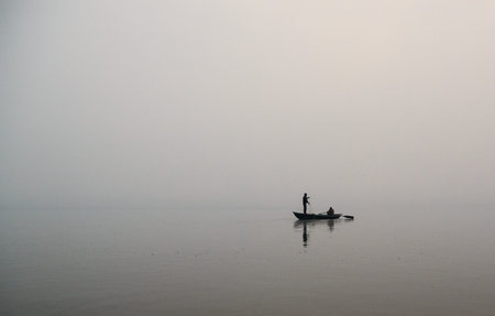 Fisherman in a boat on a foggy morningの写真素材