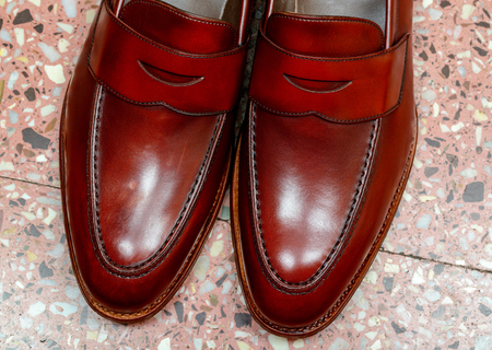 Pair of leather cherry calf penny loafer shoes on the stone floor together one by one closely. Close upの写真素材