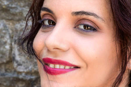 A smiling young woman looking at the camera with vivid and cheerful eyesの写真素材