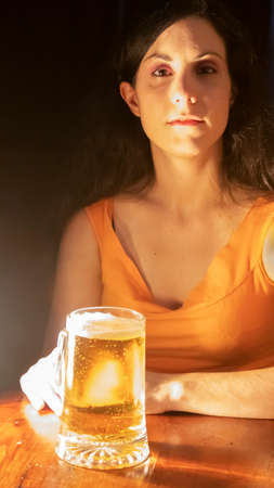 A young woman determined to drink a mug of beerの写真素材