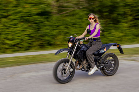 Young woman riding a motorcycle on the road. Blurred motion.の写真素材