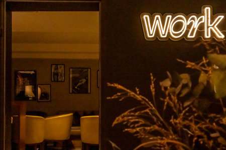 A dimly lit, stylish interior featuring a neon sign that reads 'Work'. The scene is framed by a...
