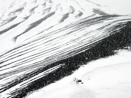 A snowy mountain landscape with distinct black and white patterns created by snow and rock
