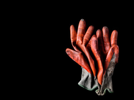 Dirty worn orange rubber coated work gloves on blackの写真素材
