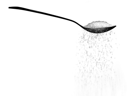 Spoonful of sugar or salt falling isolated on whiteの写真素材