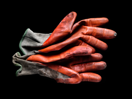 Dirty worn orange rubber coated work gloves on blackの写真素材