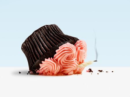 Dropped cupcake with candle and smoke on blue backgroundの写真素材