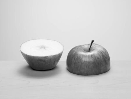 Two halves of a cut apple side by side on wood table. Black and whiteの写真素材