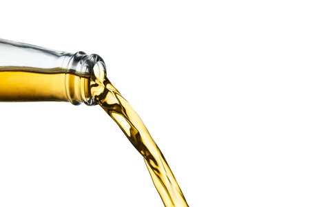 Closeup of golden ale pouring from clear bottle isolated on white background.の写真素材