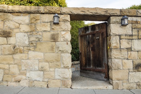 An old wood door stands ajar along a sandstone wallの写真素材