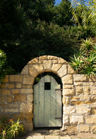 An old gate surrounded by a sandstone wall shows weathered character and ageの写真素材