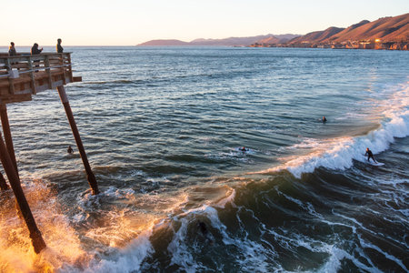 Pismo Beach California surfers catch a wave in the sunset