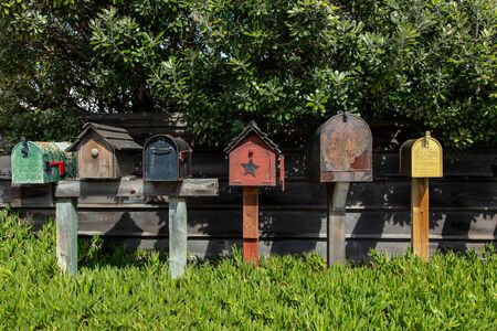 A lineup of various styles of mailboxes along a garden wall outdoors in Monterey, Californiaの写真素材