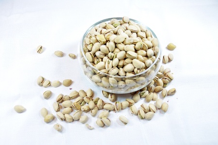 Clear glass bowl filled with pistachios on a white backgroundの写真素材