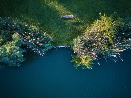 Top View of a small lake and green trees around with a small path or streetの写真素材