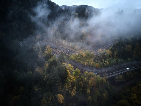 street from above trough a misty forest at autumn, aerial view flying through the clouds with fog and treesの写真素材