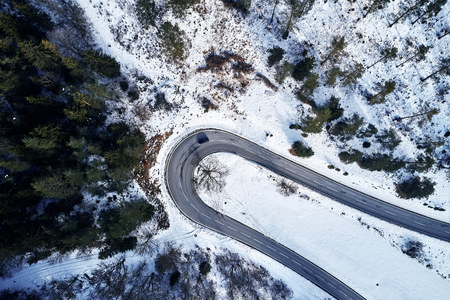 curved road in winter mountain landscape. Aerial view of forest and trees with a winding street surrounded by snow.の写真素材