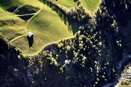 Scenic aerial panoramic view of idyllic rolling hills spring landscape in the Alps with lush green mountain pastures and wood housesの写真素材