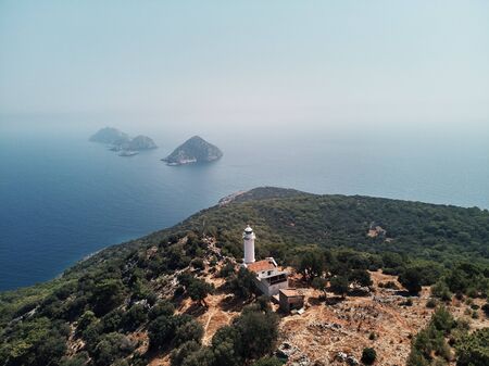 Drone shot of the lighthouse with little islands in the background on the blue ocean. Warm hot summer mood in turkey at coast.の写真素材