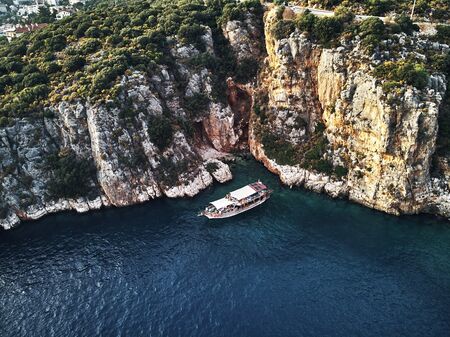 ship from above aerial drone view. Blue deep water near the stony coast. people swimming around. Beautiful seacoast, south of the Turkey.の写真素材