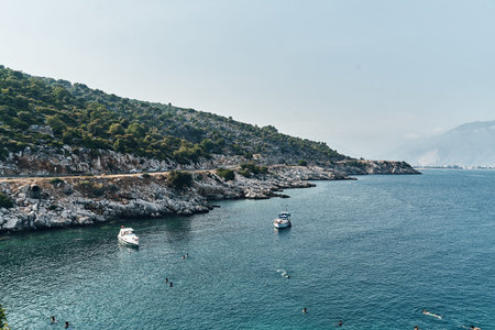 Brown rocks and sharp stones in the greenish blue water of Aegean sea near the shores of Demre city....