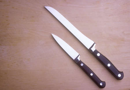 Two kitchen knives on wooden chopping boardの写真素材