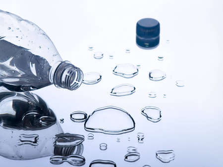 The photo shows a lying plastic bottle and some water dropsの写真素材
