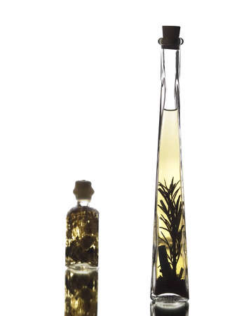 The photo shows a smal bottle filled with bathoil and a bottle filled with vinegar over a mirrorの写真素材
